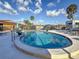 Relaxing community pool area with lounge chairs and clear blue water, surrounded by palm trees and lush landscaping at 2600 N Paula Dr # 2B, Dunedin, FL 34698
