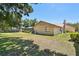 Backyard with a green lawn, mature trees, and the exterior of the home with a screen-enclosed lanai at 2914 Timber Knoll Dr, Valrico, FL 33596