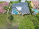 Aerial view of a home with a screened pool, well-maintained yard, and tropical trees at 3168 Masters Dr, Clearwater, FL 33761
