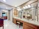 Bathroom vanity with granite counters, seating, and mirrors over cabinets and drawers with lighting fixtures at 3168 Masters Dr, Clearwater, FL 33761