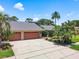 Spacious home with a three-car garage, a gray roof and beautiful landscaping at 3168 Masters Dr, Clearwater, FL 33761