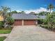 Spacious home with a three-car garage, a gray roof and beautiful landscaping at 3168 Masters Dr, Clearwater, FL 33761