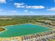 Aerial view of homes near a lake within the community with neighborhood streets, lush trees and blue sky at 31779 Asbury Ave, Wesley Chapel, FL 33545