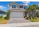 Charming two-story home featuring a well-manicured lawn, palm trees, paved driveway, and a two-car garage at 31779 Asbury Ave, Wesley Chapel, FL 33545