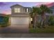 Charming two-story home features a two-car garage, brick driveway, and well-maintained landscaping at dusk at 31779 Asbury Ave, Wesley Chapel, FL 33545