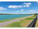 A paved walking path adjacent to a tranquil lake with clear blue water on a bright day at 31779 Asbury Ave, Wesley Chapel, FL 33545