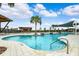 Community pool featuring shallow wading area, seating, sunshades, palm trees, and lounge chairs at 31779 Asbury Ave, Wesley Chapel, FL 33545