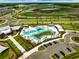 Aerial view of a community pool with winding lagoon, seating, sunshades, palm trees, and parking lot at 31779 Asbury Ave, Wesley Chapel, FL 33545