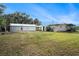 Exterior view of the home, metal sheds, carport, and spacious green backyard with fence in this property at 3407 Cason Rd, Plant City, FL 33566