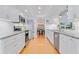 Bright kitchen with stainless steel appliances, white cabinets, and wood floors throughout at 3408 90Th N Ter, Pinellas Park, FL 33782