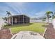 Spacious backyard featuring a screened-in patio, lush green lawn, and a partial view of surrounding properties at 3516 Casablanca Ave, St Pete Beach, FL 33706