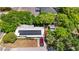 Bird's eye view of a single-story home with a metal roof, solar panels, driveway, and surrounding trees at 38351 7Th Ave, Zephyrhills, FL 33542