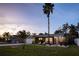 Charming single-story home featuring a well-manicured lawn, lush landscaping, and inviting front porch at dusk at 3981 Mckay Creek Dr, Largo, FL 33770