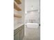 Modern bathroom featuring a soaking tub and grey vanity with gold hardware at 4607 W Lamb Ave, Tampa, FL 33629