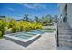 A modern outdoor pool and jacuzzi are surrounded by lush tropical landscaping and travertine tile at 4607 W Lamb Ave, Tampa, FL 33629