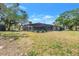 A backyard view showing a screened-in pool with a large grassy area surrounded by trees at 5065 Shore Acres Ne Blvd, St Petersburg, FL 33703