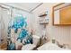 The bathroom features a toilet and shower with a turtle patterned shower curtain and open shelving at 5428 Joyce St, Zephyrhills, FL 33542