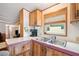 Efficient kitchen with double sink, wood cabinets, and adjacent living area at 5428 Joyce St, Zephyrhills, FL 33542