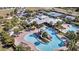 Aerial view of community pool with winding slide, palm trees, lounge chairs, and nearby tennis courts at 5486 Summer Sunset Dr, Apollo Beach, FL 33572