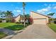 Charming home with lush lawn and mature landscaping leading to an attached two-car garage at 6104 Schooner Way, Tampa, FL 33615