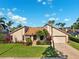 Well-maintained home with a lush green lawn, mature palm trees, and a two-car garage at 6104 Schooner Way, Tampa, FL 33615