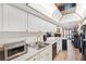 Bright kitchen features white cabinets, tile flooring, and stainless steel appliances, with view to fireplace at 6104 Schooner Way, Tampa, FL 33615