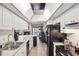 Bright kitchen with white cabinets, black appliances, with view to fireplace at 6104 Schooner Way, Tampa, FL 33615