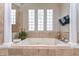 Elegant bathroom with a large soaking tub, travertine tile, and a TV for ultimate relaxation at 6201 Marbella Blvd, Apollo Beach, FL 33572