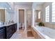 Bathroom boasting a soaking tub, granite countertops, dark wood cabinets, tile floors and glass block window at 6201 Marbella Blvd, Apollo Beach, FL 33572