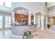 Spacious kitchen with large curved bar, granite countertops, tiled floor, stainless steel appliances, and bright lighting at 6201 Marbella Blvd, Apollo Beach, FL 33572