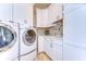 Well-organized laundry room with front loading washer and dryer, cabinets, sink and stone tile backsplash at 6201 Marbella Blvd, Apollo Beach, FL 33572