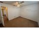 A bright, carpeted bedroom with a fan, closet, and view to the hallway at 7326 Cutwater Ln, Wesley Chapel, FL 33545