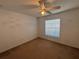 A cozy carpeted bedroom featuring a ceiling fan and window at 7326 Cutwater Ln, Wesley Chapel, FL 33545