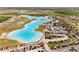 Aerial view of a community lagoon surrounded by houses, a parking lot, and highway at 8946 Ivy Stark Blvd, Wesley Chapel, FL 33545