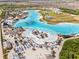 An aerial view showcases a beach and lagoon in a vibrant community with white homes and lush greenery at 8946 Ivy Stark Blvd, Wesley Chapel, FL 33545
