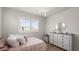 Bright bedroom featuring a window with shutters, a dresser, and decor at 8946 Ivy Stark Blvd, Wesley Chapel, FL 33545