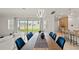 Dining area with modern chandelier, large table with blue chairs, and access to the backyard at 8946 Ivy Stark Blvd, Wesley Chapel, FL 33545