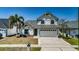 Charming two-story home featuring a two-car garage, well-maintained lawn, and a palm tree at 10906 Kenbrook Dr, Riverview, FL 33578