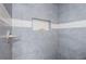 Close-up of a modern shower featuring gray tiled walls, a built-in niche, and a sleek shower handle at 10906 Kenbrook Dr, Riverview, FL 33578