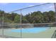 Fenced tennis court surrounded by trees, ideal for sports and recreation at 10906 Kenbrook Dr, Riverview, FL 33578