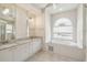 Bathroom featuring dual sinks, large window, and garden tub for relaxation at 11147 Brambleleaf Way, Hudson, FL 34667
