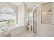 Bright bathroom featuring garden tub, glass shower, and white tile flooring at 11147 Brambleleaf Way, Hudson, FL 34667