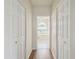 Hallway view showcasing wood floors, white doors, and an opening to the Primary bathroom at 11147 Brambleleaf Way, Hudson, FL 34667