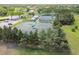 Aerial view showcases community tennis courts surrounded by lush greenery and ample parking at 11147 Brambleleaf Way, Hudson, FL 34667