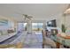 Bright living room featuring a ceiling fan, wood floors, and sliding glass doors with water views at 1301 Gulf Blvd # 107, Clearwater Beach, FL 33767