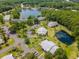 Aerial view showcases a pond, mature trees, and the community buildings with ample parking at 1400 Pine Glen Ln # B2, Tarpon Springs, FL 34688