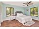 Bedroom with aqua walls, a queen bed, and two windows with views of the trees at 1400 Pine Glen Ln # B2, Tarpon Springs, FL 34688