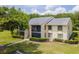 View of a two-story condo featuring a screened patio, manicured shrubs, and an assigned parking spot at 1400 Pine Glen Ln # B2, Tarpon Springs, FL 34688