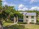 View of the neutral-toned exterior of this two-story condominium building showcasing a large shade tree and lush landscaping at 1400 Pine Glen Ln # B2, Tarpon Springs, FL 34688