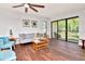 Bright living room featuring wood-look floors, modern furnishings, and a glass slider leading to a screened lanai at 1400 Pine Glen Ln # B2, Tarpon Springs, FL 34688